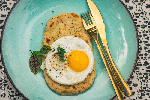 Fried egg with flat bread pizzaon a blue and white background. Top view of table, close-up. photo