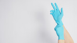 The hand is pulling a blue surgical glove or latex gloves on a white background.