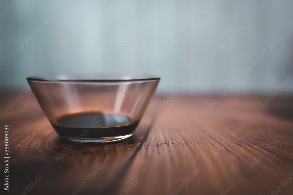 A measure of 1 TBSP of Soya Sauce in a transparent glass bowl on a brown wooden table with bright wooden background. Free space for your decoration/text. A measure of 1 TBSP of Soya Sauce in a transparent glass bowl on a brown wooden table with bright wooden background. Free space for your decoration/text.