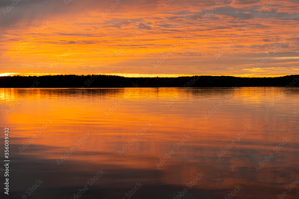 Water surface. Sunset sky background. Gold sunset sky with evening sky clouds over the lake. Small waves. Water reflection