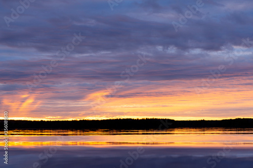 Water surface. Sunset sky background. Gold sunset sky with evening sky clouds over the lake. Small waves. Water reflection