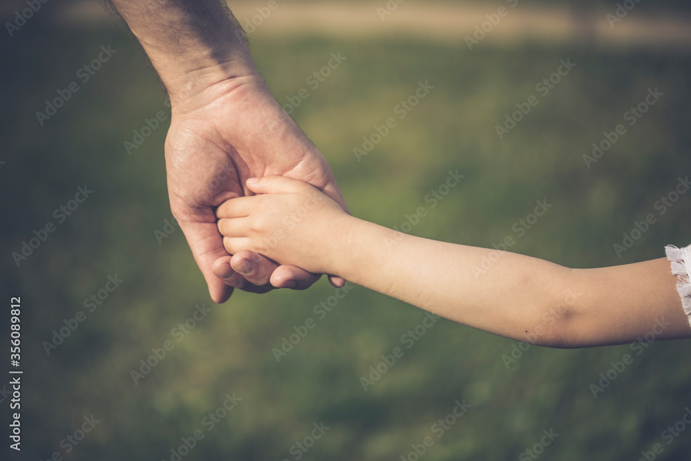 Parent holding the hand of a small child. Father's hand lead his child in summer nature outdoor. Family or fathers day concept. Parent holding the hand of a small child. Father's hand lead his child in summer nature outdoor. Family or fathers day concept.