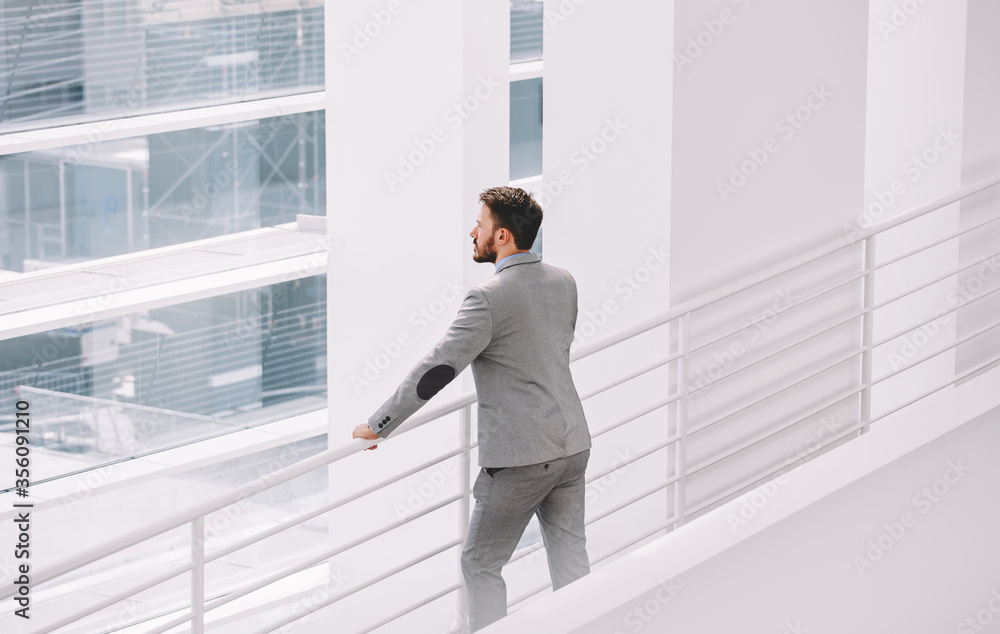 Half length portrait of rich businessman holding portable digital tablet during work break in hallway Half length portrait of rich businessman holding portable digital tablet during work break in hallway