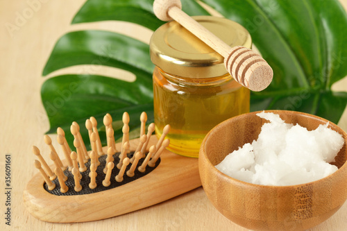 Honey and cononut oil in wooden bowl with hair brush - Homemade hair mask ingredients photo