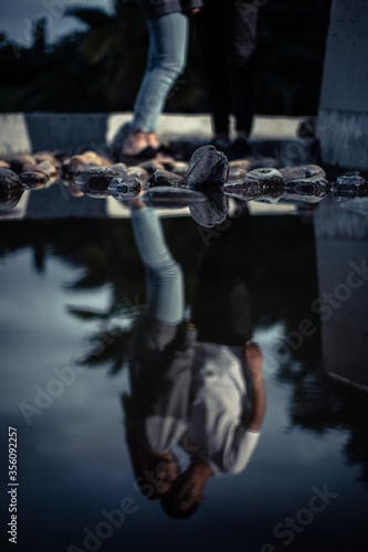 reflection in the water of a young couple kissing and hugging during night time