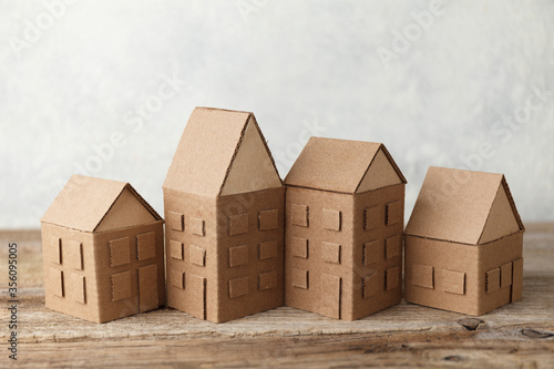 Cardboard toy houses on wooden background. Sale or rental of housing. Neighbors in house. Comfortable life in suburbs.