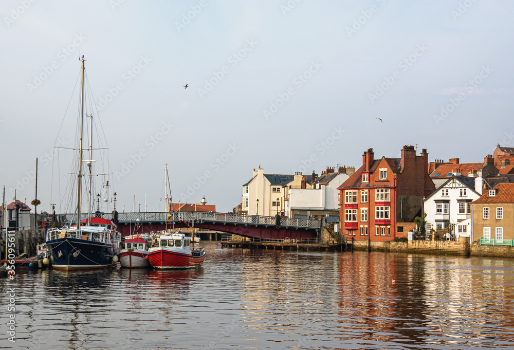 Fishing boats anchored in the harbor at Whitby. The picturesque Yorkshire town in the north of England glows in autumn evening sunshine. Fishing boats anchored in the harbor at Whitby. The picturesque Yorkshire town in the north of England glows in autumn evening sunshine.