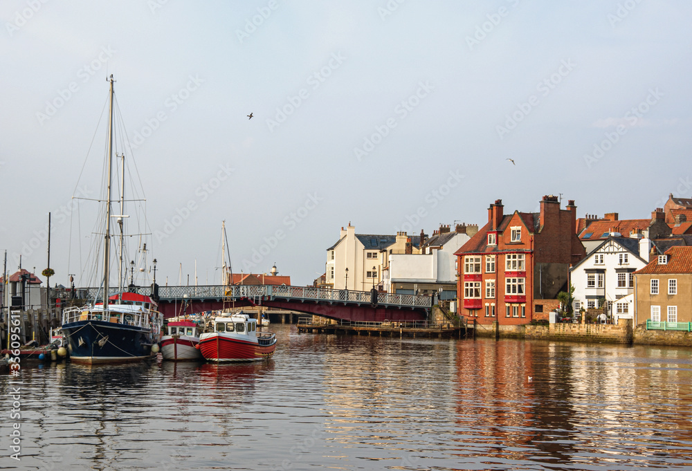 Fishing boats anchored in the harbor at Whitby. The picturesque Yorkshire town in the north of England glows in autumn evening sunshine.