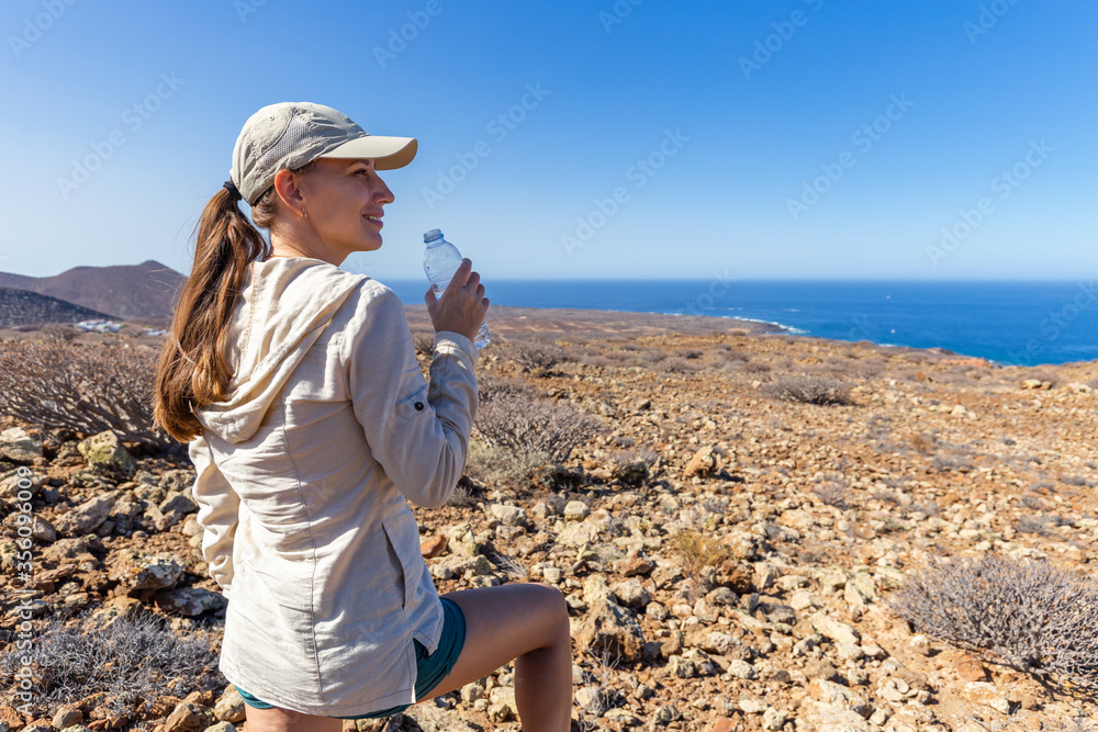 Young hiking woman drinks water in south Tenerife