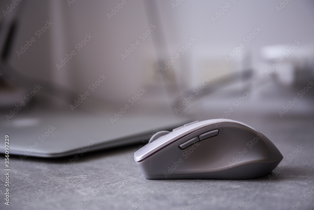 Grey wireless computer mouse lying on a desk near a notebook Grey wireless computer mouse lying on a desk near a notebook