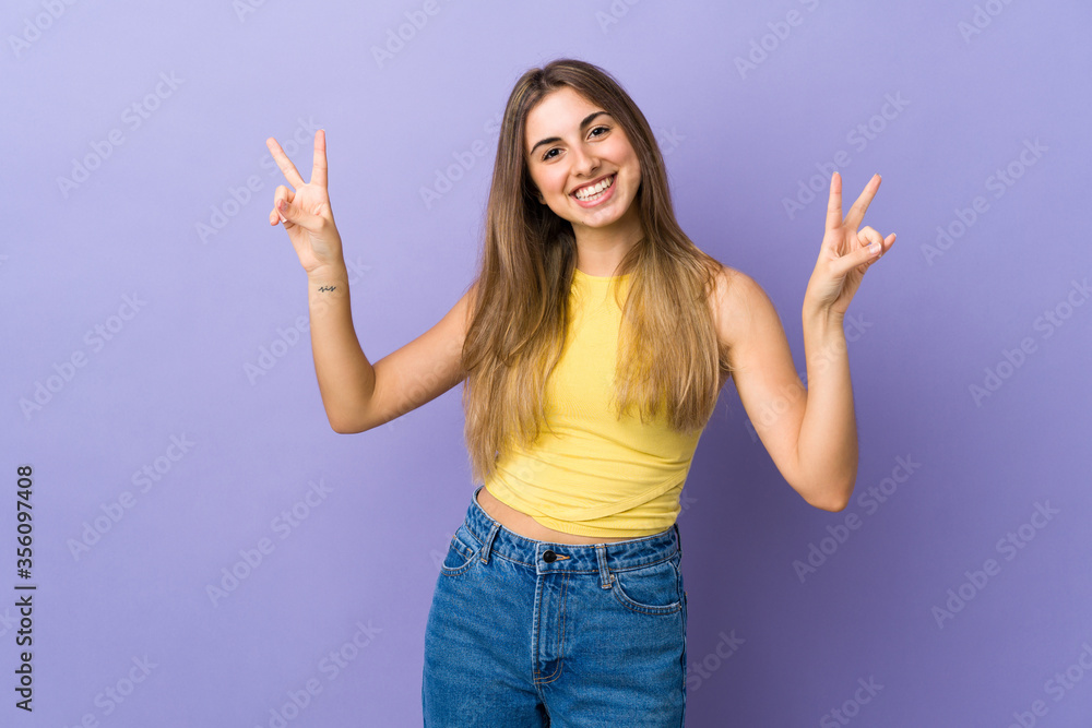 Young woman over isolated purple background showing victory sign with both hands