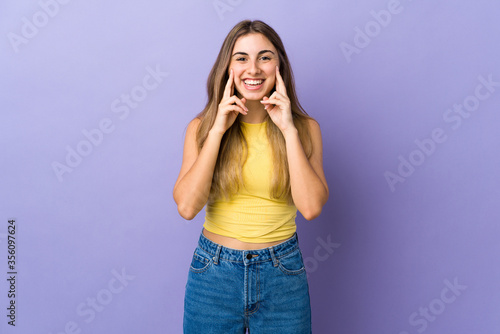 Young woman over isolated purple background smiling with a happy and pleasant expression