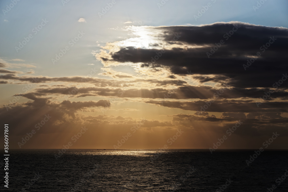 Sunbeams and dark clouds over sea during sunset Sunbeams and dark clouds over sea during sunset