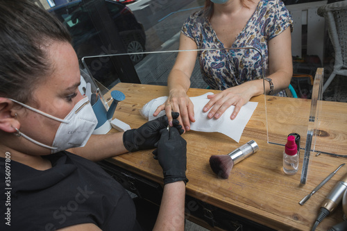 mujeres trabajando en centro de belleza, estética y bienestar con las mascarillas y EPIS reglamentarios por el virus COVID-19 photo