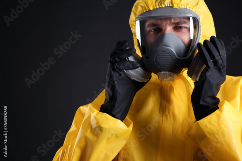 Obraz na płótnie Man wearing chemical protective suit on black background, closeup