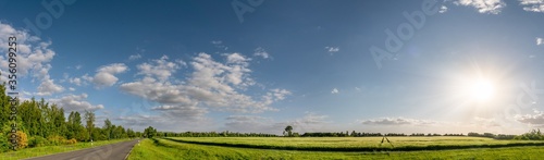 cloudy blue sky over green fields in spring with beautiful bright sun rays