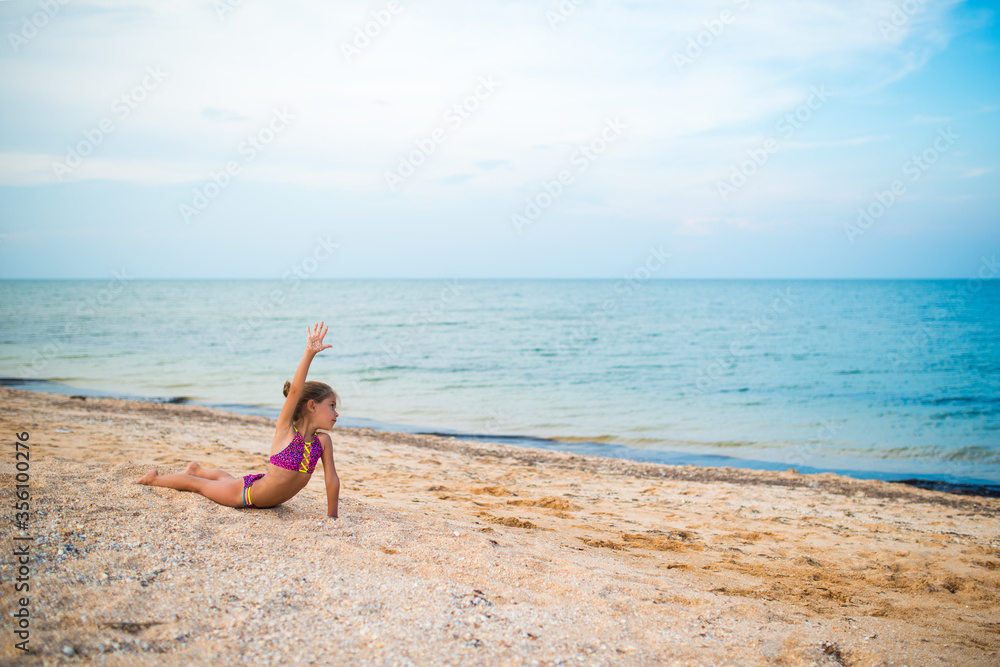 Girl do gymnastic exercises on the beach.