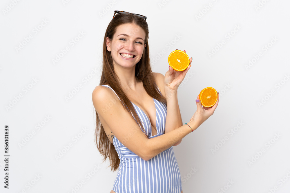 Young caucasian woman isolated on white background in swimsuit and holding an orange Young caucasian woman isolated on white background in swimsuit and holding an orange