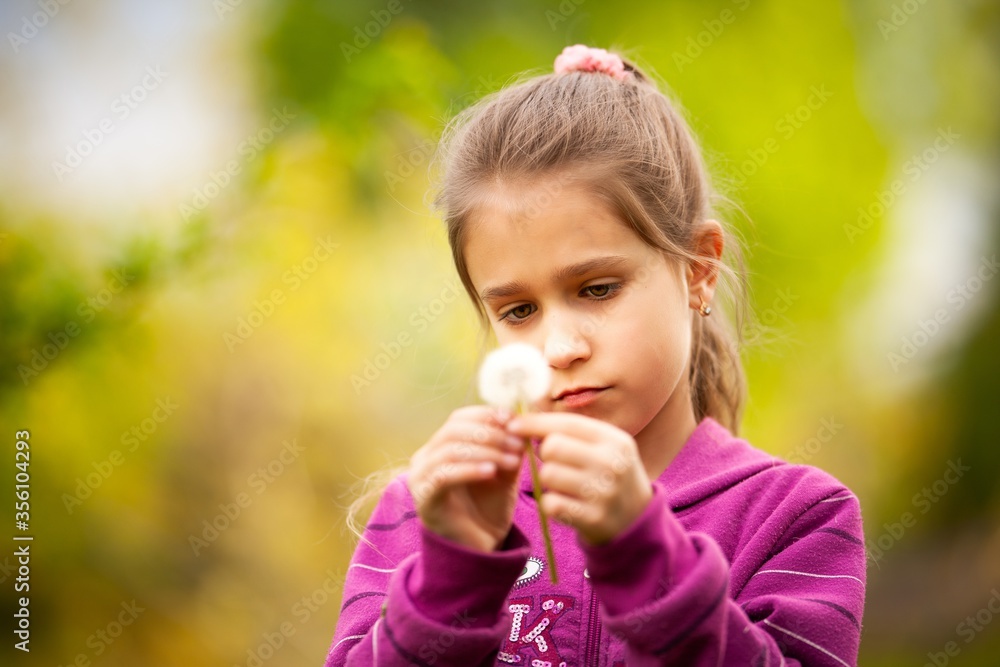 Little beautiful girl holds spring dandelion in her hand. Summer fun, sweet girl dandelion on the meadow Little beautiful girl holds spring dandelion in her hand. Summer fun, sweet girl dandelion on the meadow