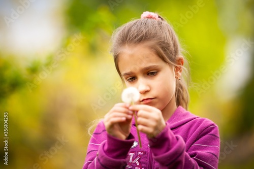 Little beautiful girl holds spring dandelion in her hand. Summer fun  sweet girl dandelion on the meadow