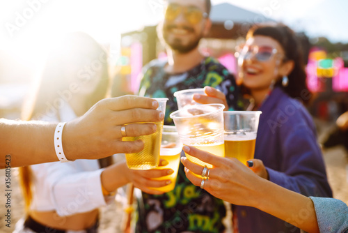 Group of friends with beer dancing and having fun at music festival together. Summer Beach party, holiday, vacation concept.Youth and celebration concept.
