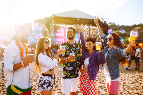 Group of friends with beer dancing and having fun at music festival together. Summer Beach party, holiday, vacation concept.Youth and celebration concept. 
