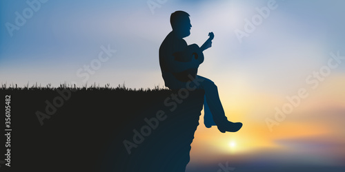 Concept de l’inspiration et de la méditation avec un musicien seul, qui joue de la guitare assis au bord d’une falaise.