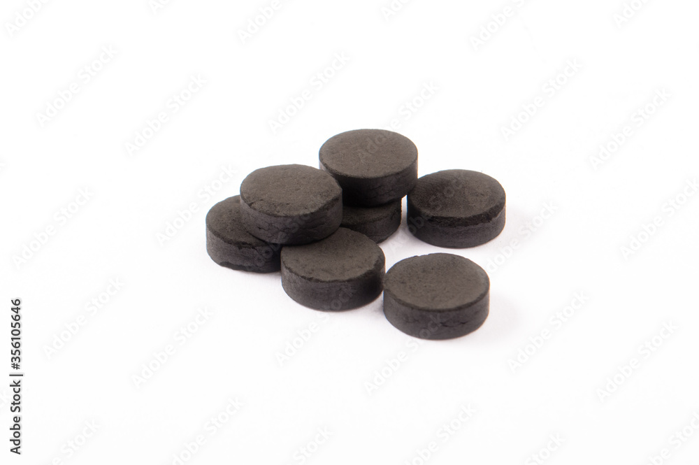 Activated carbon in tablets isolated on white. Health concept Activated carbon in tablets isolated on white. Health concept
