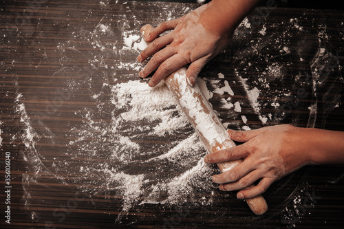 Rolling pin and flour on a wooden table. Hands on a rolling pin. Close-up photo