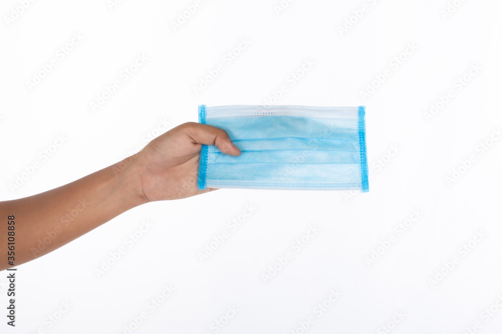 Hand of woman holding surgical face mask, studio light shooting isolated on white background, coronavirus, COVID19 concept Hand of woman holding surgical face mask, studio light shooting isolated on white background, coronavirus, COVID19 concept