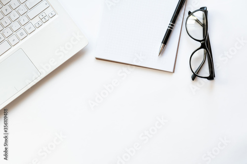Workplace with notebook, glasses, pen and notepad on light white backround. Copy space. Top view. Concept business.