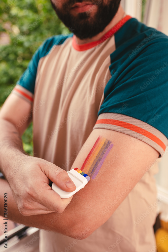 Man painting a lgbt rainbow flag with a fan brush in the arms Man painting a lgbt rainbow flag with a fan brush in the arms
