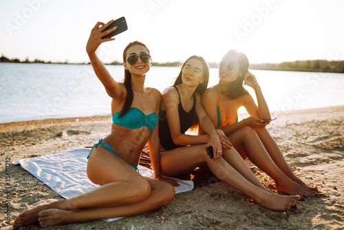 Young girls take selfie on the beach. Beach holiday and summer vacation concept.