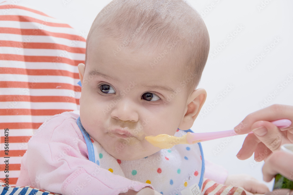 Feeding the baby with a spoon. A mother gives healthy food to her child at home Feeding the baby with a spoon. A mother gives healthy food to her child at home