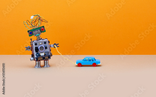 Robot plays with a vintage toy car. Orange background, copy space