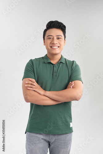 Young good looking man standing wearing a green t-shirt. White background.