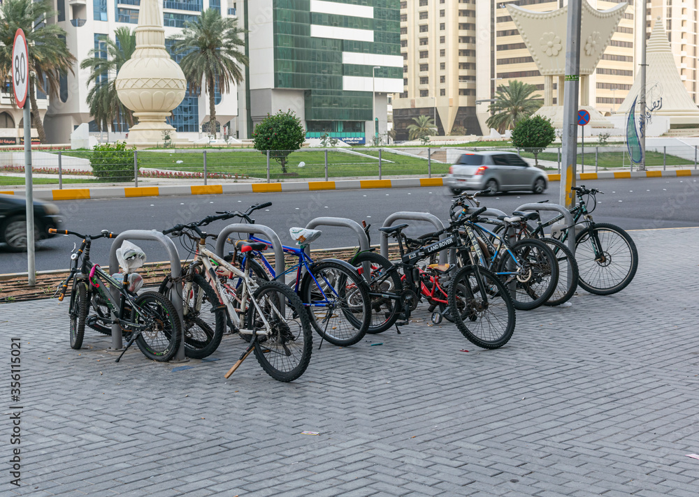 a group of bycicles parked in a parking space in abu dhabi street.a group of bicycles parked in a parking space in abu dhabi street.