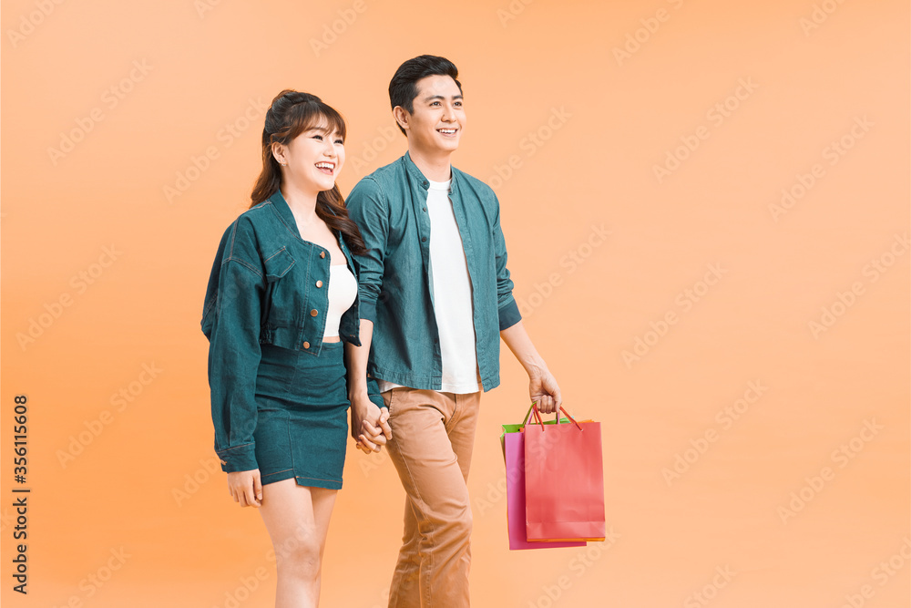 Happy asian couple holding shopping bags and smiling at camera isolated Happy asian couple holding shopping bags and smiling at camera isolated