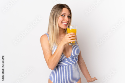 Young blonde woman isolated on white background in swimsuit and holding a cocktail