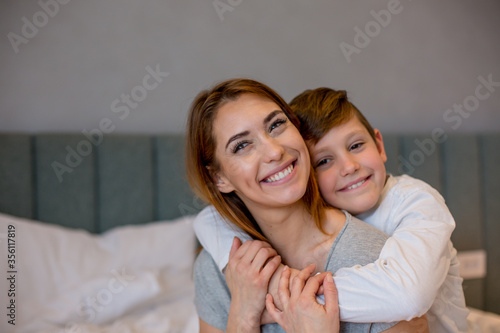 Young mother and son hugging while the son is looking at the camera