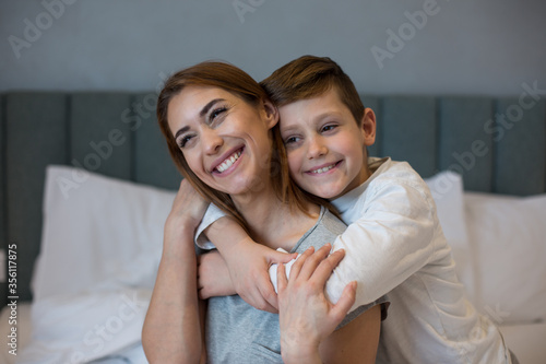 Mother and son hugging and bonding together inside the bedroom