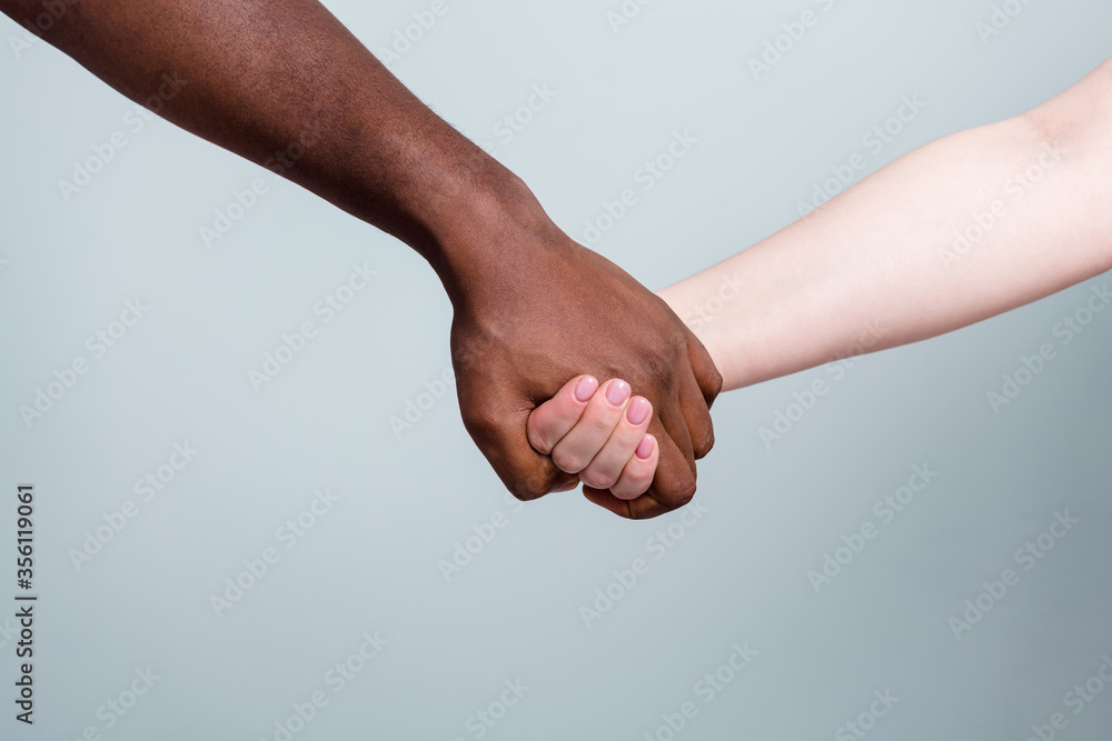 Closeup photo of two hands arms different race multinational couple best friends anti racism issue help together holding together love save world isolated grey color background Closeup photo of two hands arms different race multinational couple best friends anti racism issue help together holding together love save world isolated grey color background
