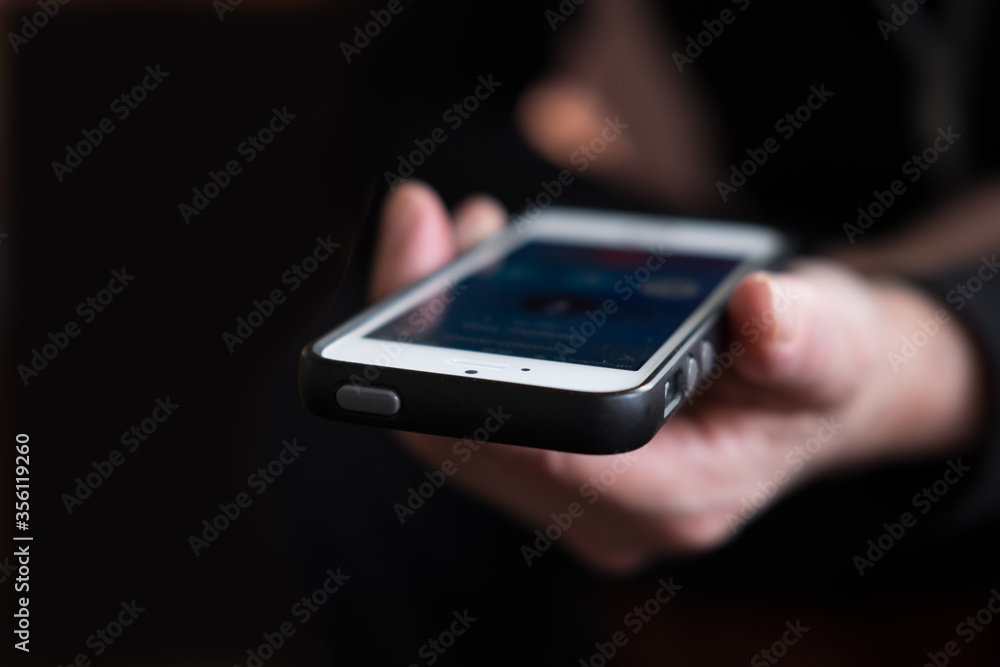 Hand holding mobile in the direction of the camera, with dark background and narrow depth of field Hand holding mobile in the direction of the camera, with dark background and narrow depth of field