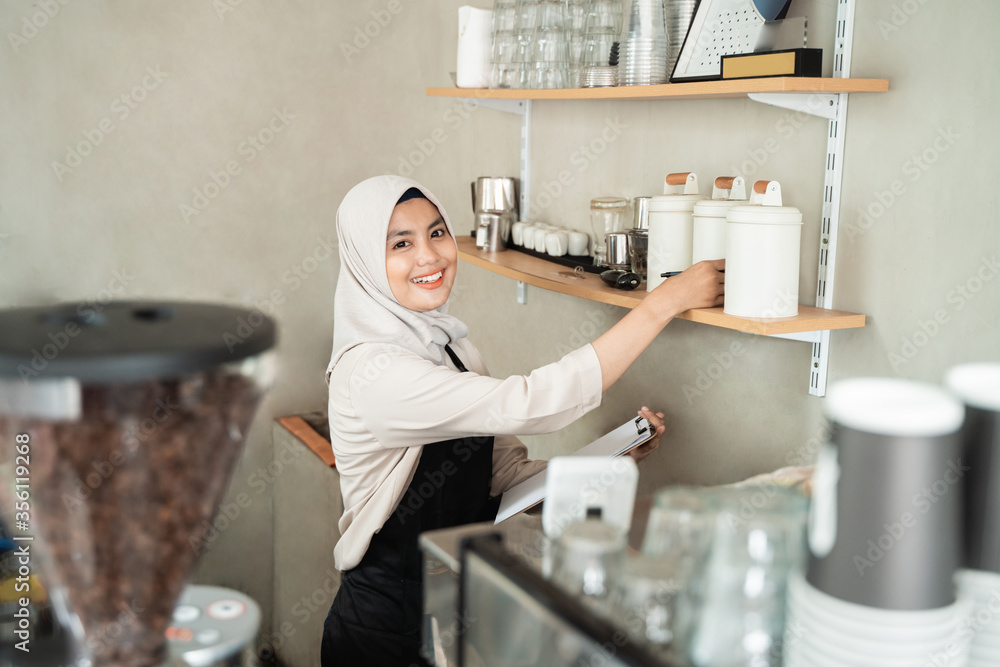 female waiter holds a bottle to check the stock of raw materials for the cafe female waiter holds a bottle to check the stock of raw materials for the cafe