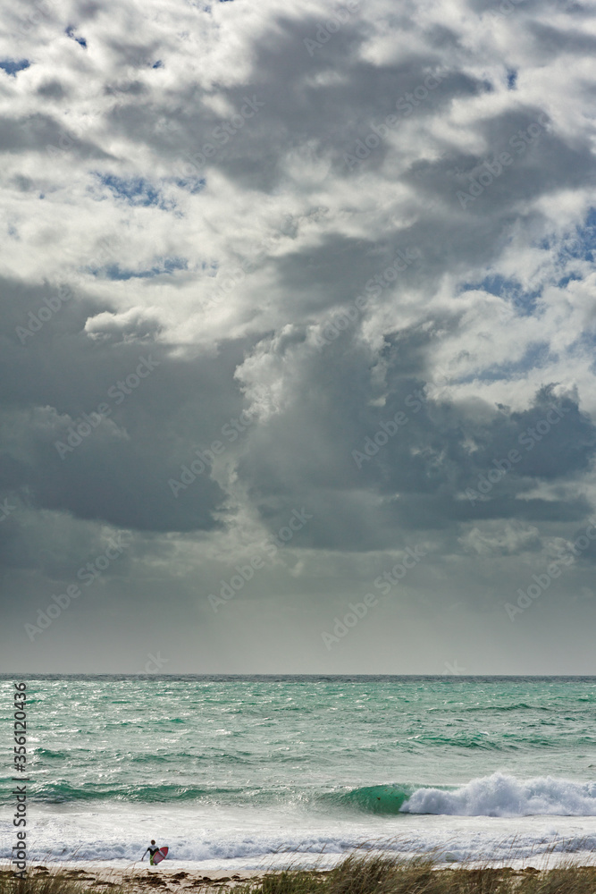 A lone surfer heading out to the waves A lone surfer heading out to the waves