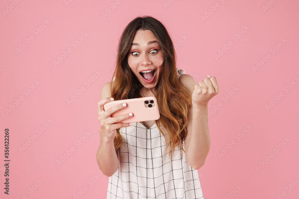 Image of excited cute woman using cellphone and making winner gesture Image of excited cute woman using cellphone and making winner gesture