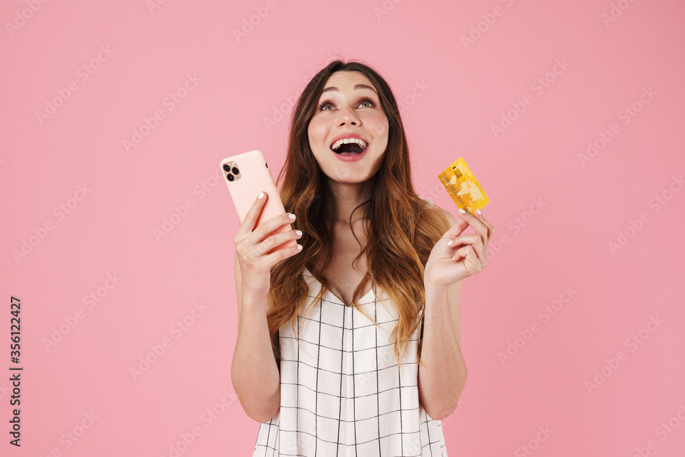 Image of delighted nice woman holding cellphone and credit card Image of delighted nice woman holding cellphone and credit card