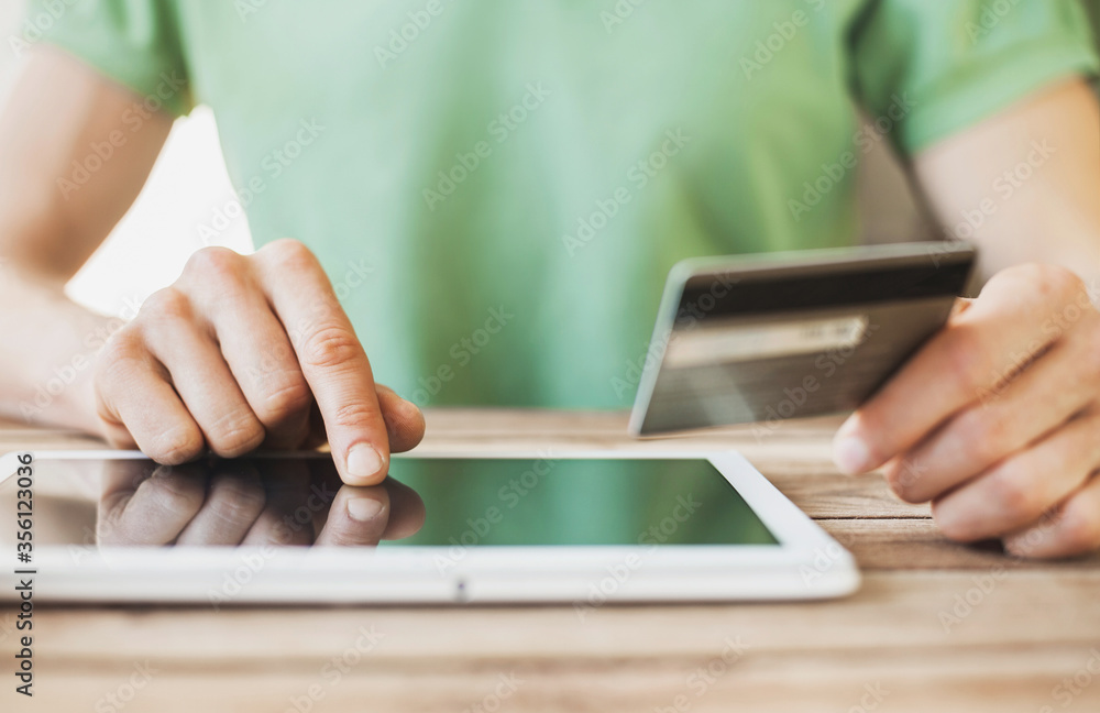 Man holding credit card and using digital tablet at home, Businessman or entrepreneur working, Online shopping, e-commerce, internet banking, spending money, working from home concept Man holding credit card and using digital tablet at home, Businessman or entrepreneur working, Online shopping, e-commerce, internet banking, spending money, working from home concept