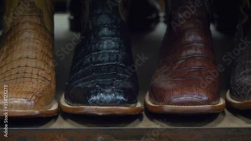 Cowboy boots on a shelf in a store, facing straight. Cowboy boots on sale on a shelf in the store indoors. American-style boots from ostrich, crocodile and buffalo leather. Cowboy boot on the shelf.