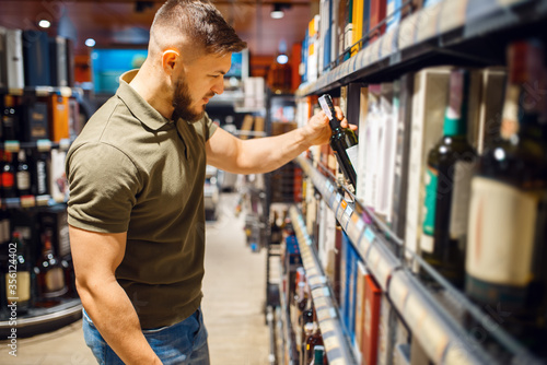 Man choosing alcohol products in grocery store